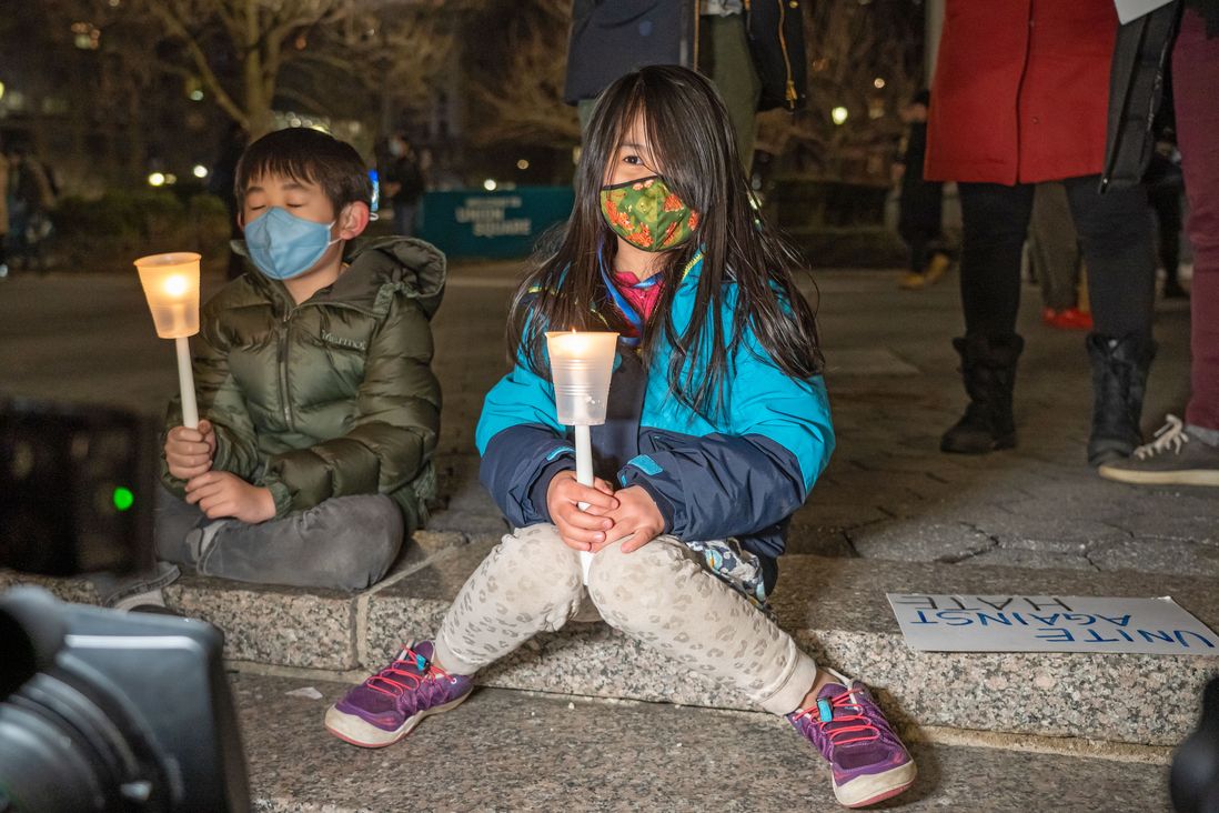 Two children sit on the steps in Union Square, holding candles